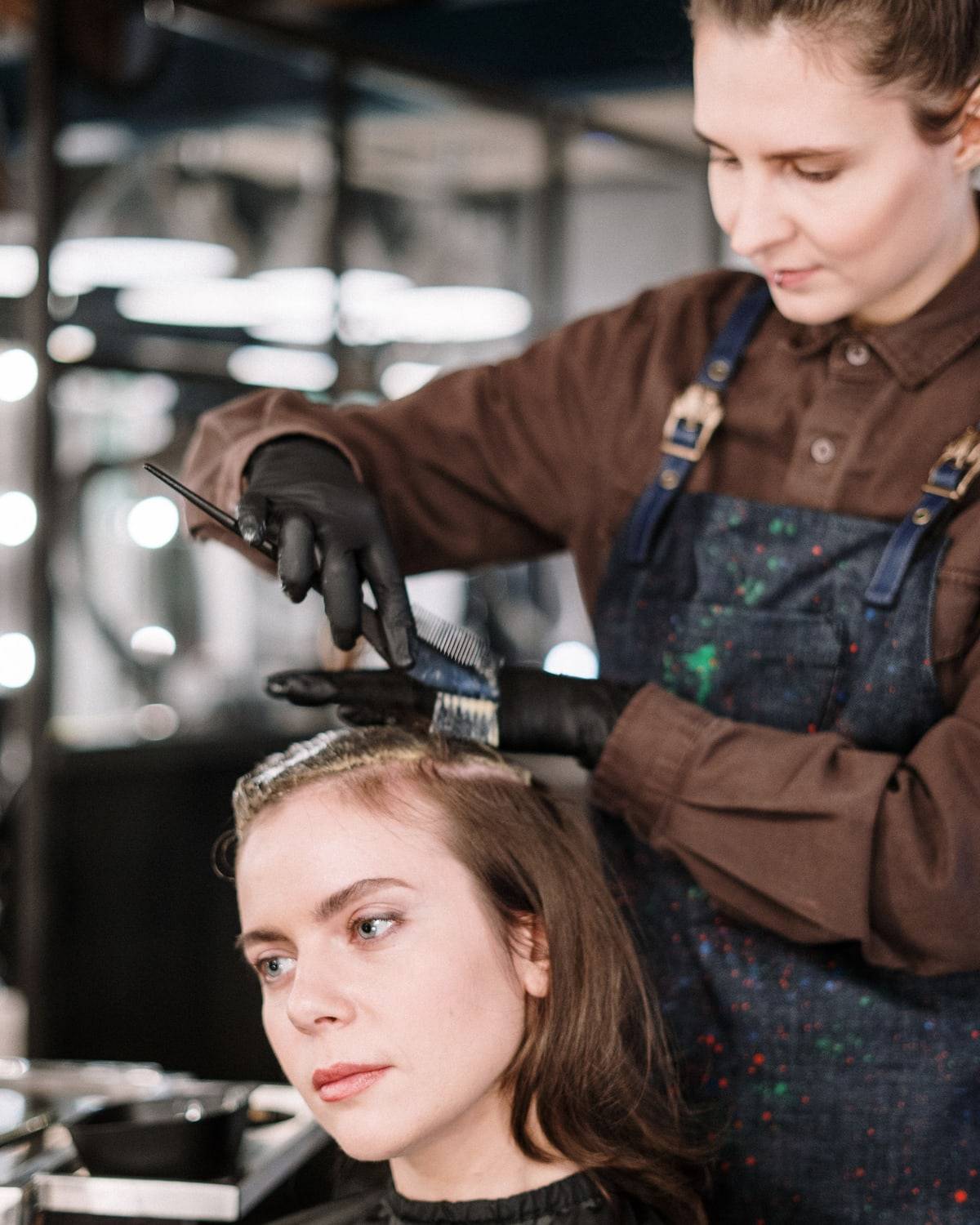 Une coloriste applique une couleur sur les cheveux d'une cliente.