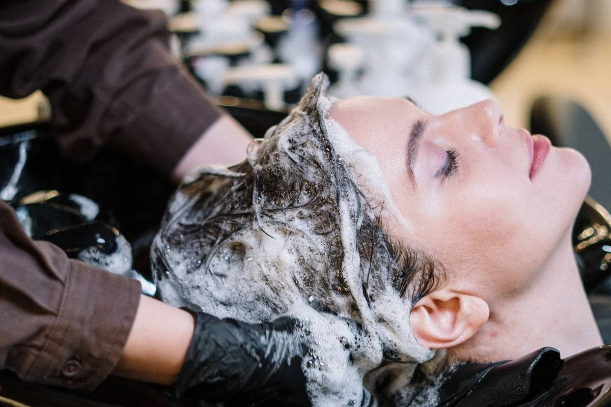 Une cliente, les yeux fermés, pendant un shampoing au bac.